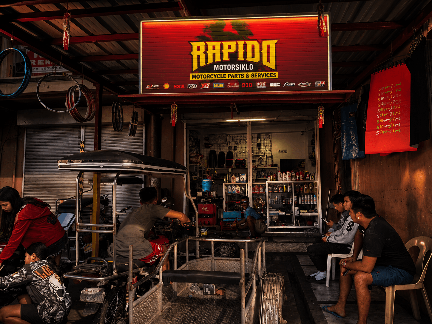 Lit Rapido Motorsiklo Garage storefront at dusk with a mechanic working on a motorcycle